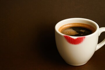A cup of coffee with a red lipstick on the side