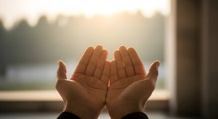 Open hands reaching towards bright light in a gesture of prayer or receiving something good