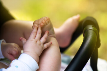 Baby in stroller holding own foot, demonstrating hand-foot coordination as developmental milestone