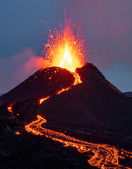 Volcanic eruption with flowing lava and fiery explosions against a dark sky.