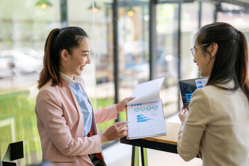 Businesswomen discussing financial charts and data analysis in modern office