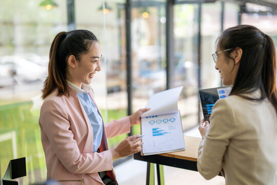 Businesswomen discussing financial charts and data analysis in modern office