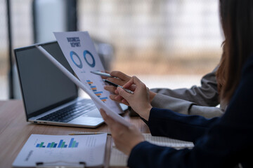 Businesswomen analyzing financial business report using laptop at office desk