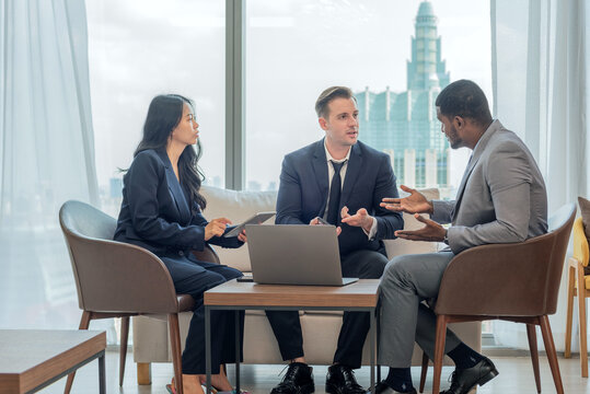 diverse group business professionals sitting on couch looking tablet. business teamwork brainstorm colleague meeting discussion strategy urban office smart working