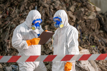 Two scientists in protective suits and masks analyzing documents outdoors in hazardous environment with warning tape and rocky background for safety research or environmental study