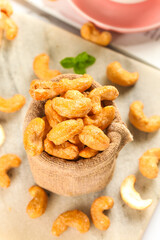 Crispy Fried Vietnamese Cashew Nuts in Rustic Burlap Sack on Wood Background