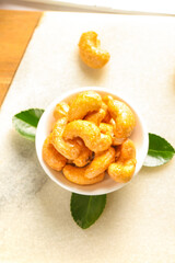 Vietnamese Salt-Baked Fried Cashews in Bowl with Green Leaves - Golden Amber Crunchy Nuts Snack Food Photography