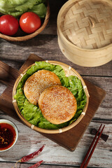 Crispy Sesame Seed Scones in Bamboo Steamer with Fresh Vegetables on Wooden Table