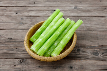 Fresh Celery Stalks in Wicker Basket on Rustic Wood Background