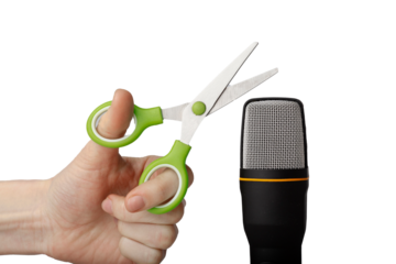 Hand holding open scissors with green handles about to cut a roll of black and white checkered tape against a Transparent PNG background