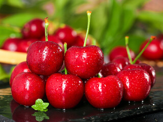 Fresh Red American Cherries with Water Drops and Green Stems on Dark Surface