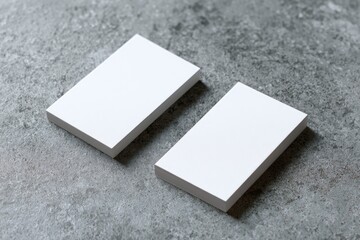 Two blank business cards lie flat on a mottled gray surface