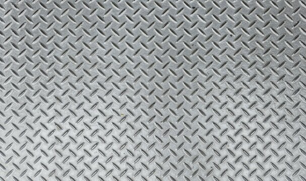 Silver steel floor. Silver steel diamond plate pattern background texture. Close-up abstract of shiny metallic silver steel plate with textured, embossed pattern.
