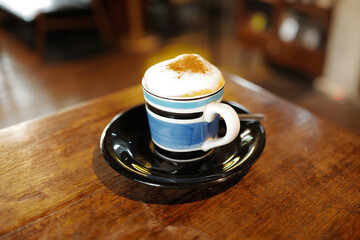 Close up ceramic mug of hot cappuccino coffee on wooden table