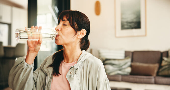 Woman, fitness or drinking with water bottle in home for hydration, sustainability or recovery. Active, female person or thirst with mineral liquid or aqua beverage for rest or workout break in house