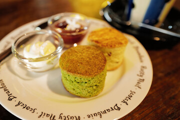 Close up Matcha green tea scone served with clotted curd cream and strawberry jam