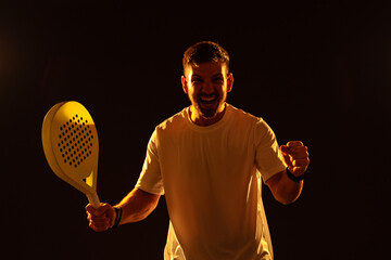 Joyful athlete celebrates victory in indoor padel game with bright studio lighting