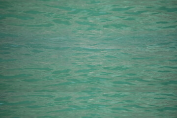 Blue water with ripples on the surface. Defocus blurred transparent blue colored clear calm water surface texture with splashes and bubbles. Water waves with shining pattern texture background.