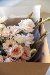 Mixed flower bouquet with roses, gerberas, and berries, carefully placed inside a cardboard delivery box, ready for gift giving