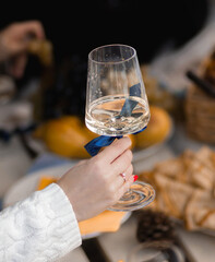 Pregnant woman at baby shower picnic in autumn nature. Female in brown coat and sweater holds sparkling wine or marshmallows, opens gifts, takes photos, laughs, enjoys time with guests outdoors