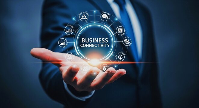 A businessman holds a glowing digital network of business connectivity icons in his open palm, symbolizing global connections and modern enterprise.