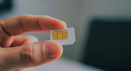 A person's fingers holding a small white SIM card with a gold chip, ready for insertion into a device.