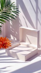 An open white gift box sits on a textured surface, next to an orange flower and a palm leaf, with dappled sunlight and shadow creating a serene atmosphere.