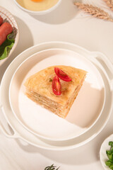 Homemade Layered Pasta Slice with Fresh Tomato Garnish on White Plate