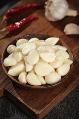 Fresh Shandong Garlic Cloves in Wooden Bowl with Red Chili Peppers on Rustic Kitchen Cutting Board