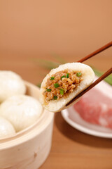 Handmade Steamed Bun with Fresh Meat and Scallion Filling Held by Chopsticks