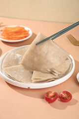 Gluten-free buckwheat crepes with chopsticks and fresh vegetables on wooden table