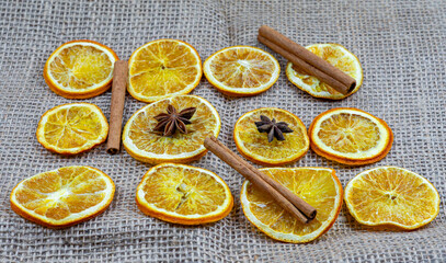 Dried orange slices, cinnamon sticks, and star anise arranged on burlap background, festive spices and Christmas decorations