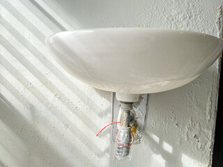 Broken washbasin drain pipe on damped, musty old painted wall with sunlight and striped shadow. Textured exterior toilet wall in room at dhamma retreat center, Saraburi, Thailand. 25 OCT 2025. A.M.