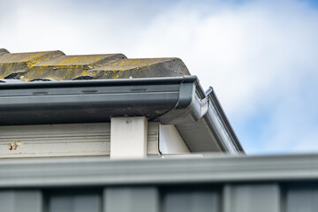 A roof corner showing guttering, drainage pipe, and roofing materials on a modern suburban house in Australia. Concept of the construction industry, property maintenance, and home improvement. © Doublelee