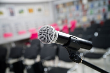 Close-up of a professional microphone on a stand in an empty conference hall before a performance. Selective focus with blurred chairs in the background and copy space. Photo