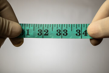 Gloved hand constrained by a tangled, green fiber-glass measuring tape