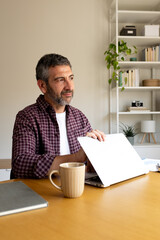Thoughtful man closing laptop, ending remote work day
