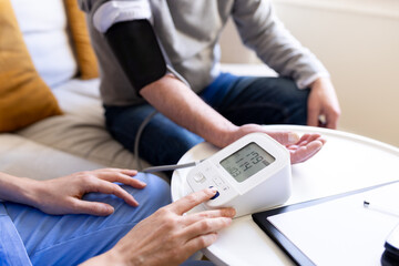 Nurse measuring blood pressure of senior man at home visit