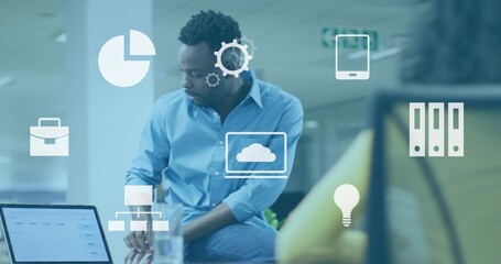 Sitting man light-blue shirt leaning on desk at office, laptop, water glass and tech icons floating