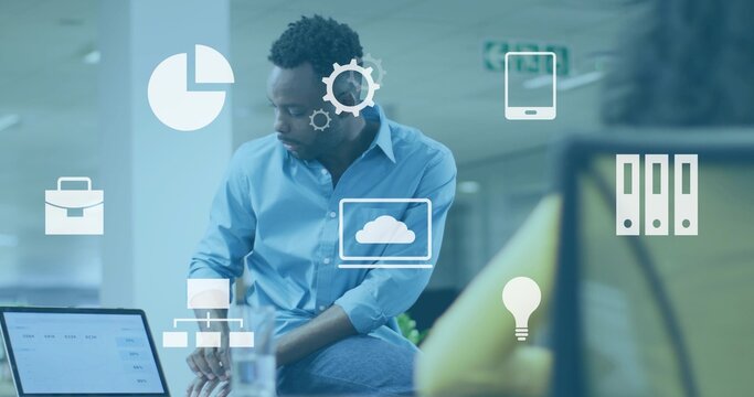 Sitting man light-blue shirt leaning on desk at office, laptop, water glass and tech icons floating