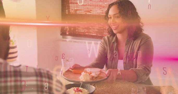 Smiling woman in green top offering sandwich to plaid shirt partner at home with floating letters - Powered by Adobe
