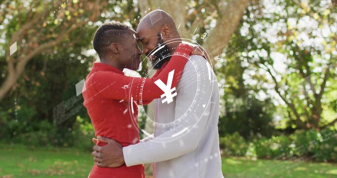 Embracing couple standing in grassy yard in red knit and gray sweaters, digital currency overlay