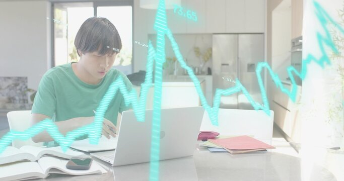 Working man in green T-shirt analyzing data on silver laptop in kitchen, with cyan chart, books