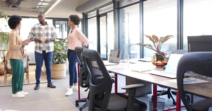 Talking man holding tablet, two women listening in office, plaid shirt, blazer, laptops, copy space - Powered by Adobe