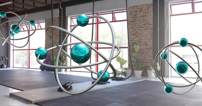 Hanging large orbital sculpture catching window light in warehouse studio, showing suspension ropes