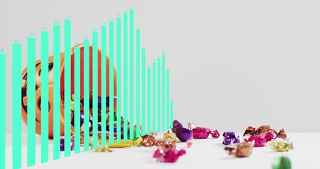 Spilling orange pumpkin bucket scattering bright foil candies across white table, turquoise bars