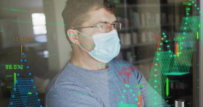 Mature man wearing surgical mask glasses blue sweater studying candlestick charts at desk monitor