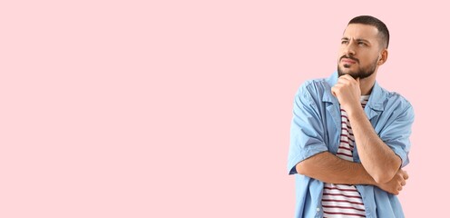 Thoughtful young man on pink background with space for text
