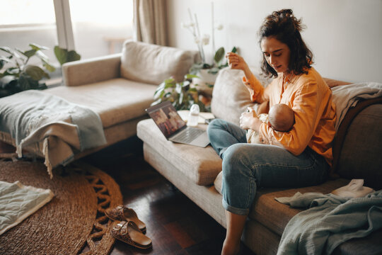 Business mother on video call at home while holding baby