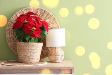 Christmas flower poinsettia with lamp on shelf near green wall